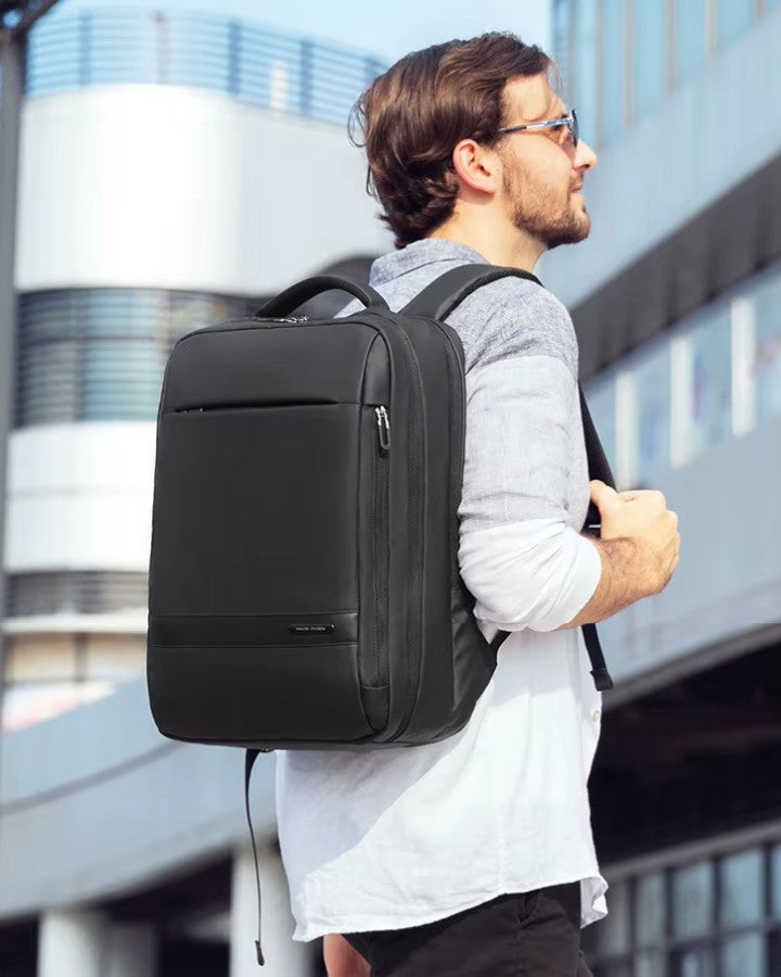 Homme portant un sac à dos 40 × 30 × 15 cm dans un décor urbain, soulignant son design professionnel et discret.