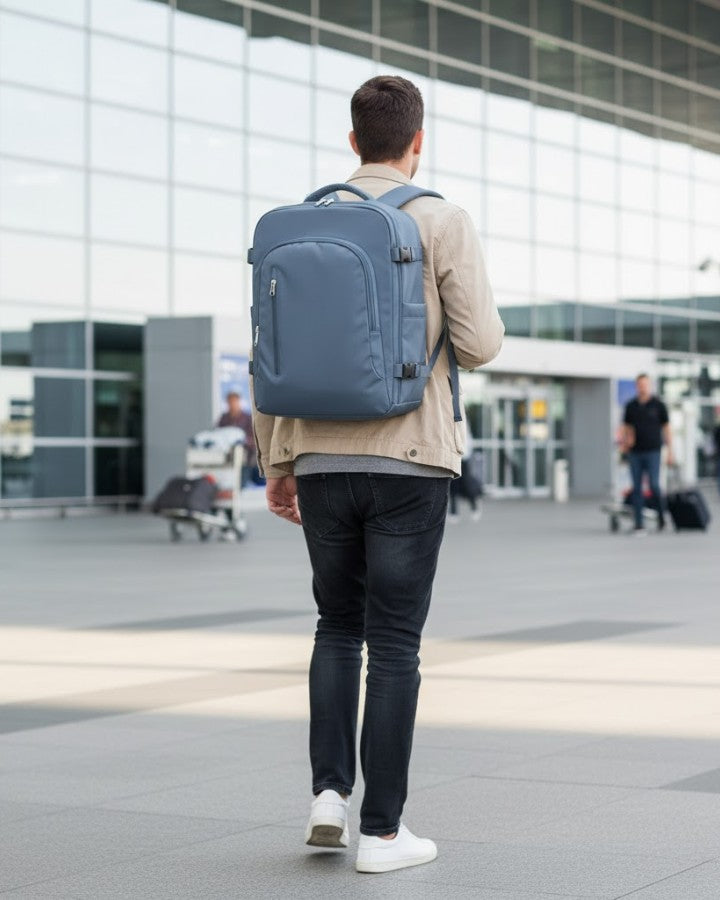 Sac à dos 45 x 36 x 20 cm porté par un homme sur le dos, devant un aéroport