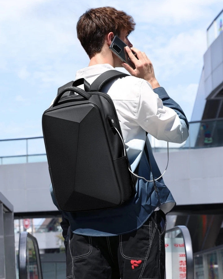 Sac à Dos Antivol pour PC 15.6" avec Port USB, porté sur le dos d'un homme, au téléphone, rechargeant son téléphone grâce au port USB intégré