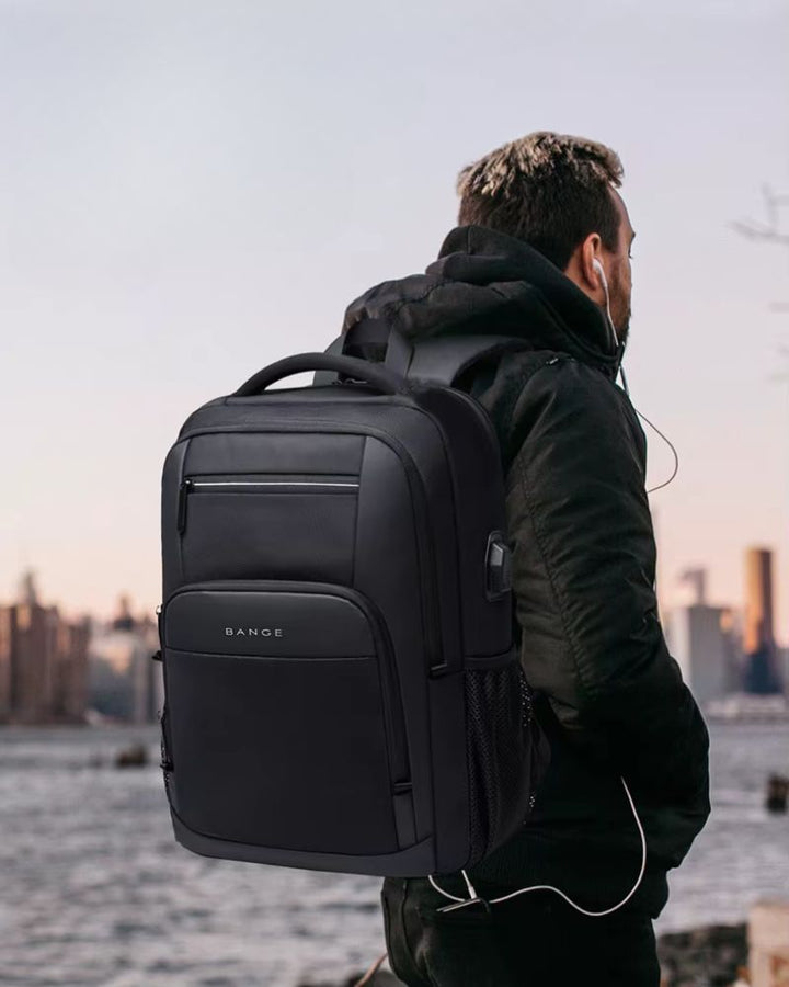 Sac à dos avec pochette ordinateur, coloris noir, porté sur le dos par une personne regardant à l'horizon et écoutant de la musique avecd des écouteurs