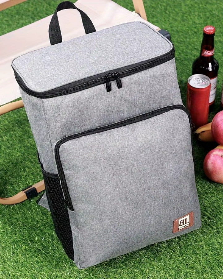 Sac à dos homme isotherme gris clair posé sur l’herbe pour sortie pique-nique
