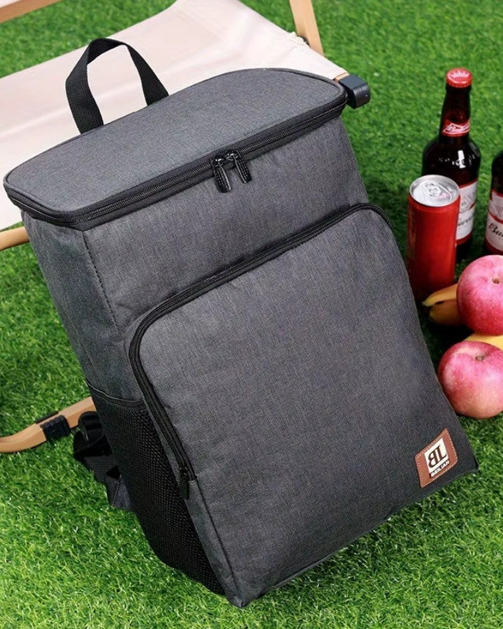 Sac à dos homme isotherme noir posé sur l’herbe avec boissons et fruits autour
