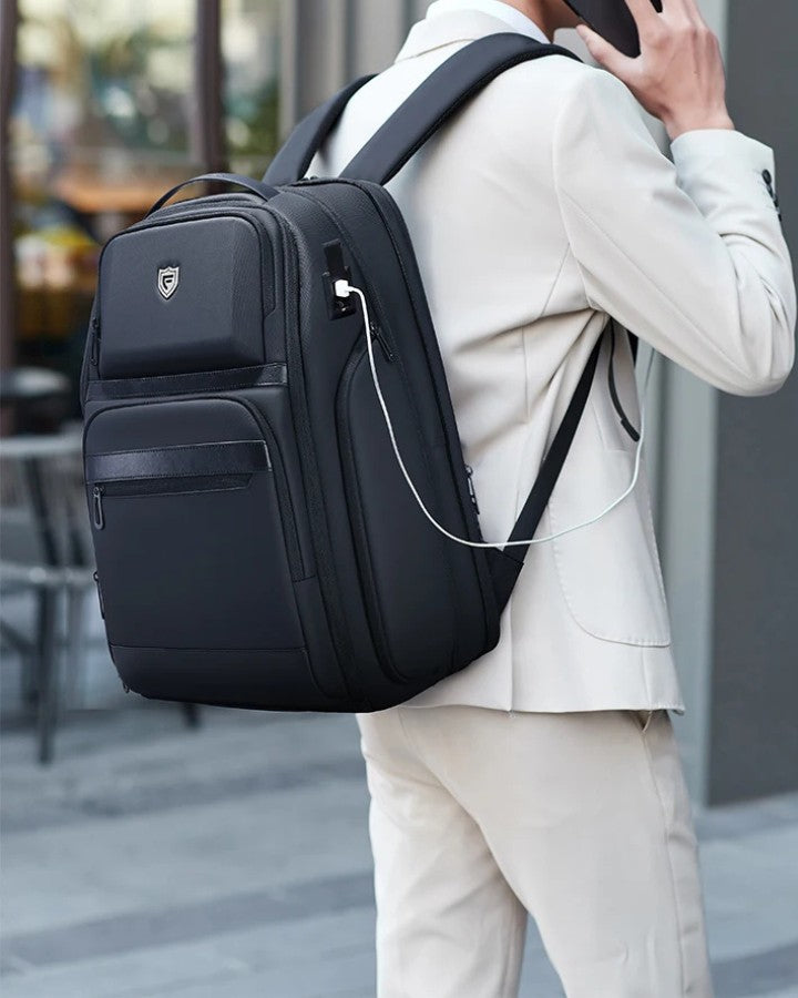 Sac à Dos Ordinateur 17.3 Pouces pour Travail, porté sur le dos d'un homme, au téléphone, rechangeant en même temps son téléphone grâce au port USB intégré au sac