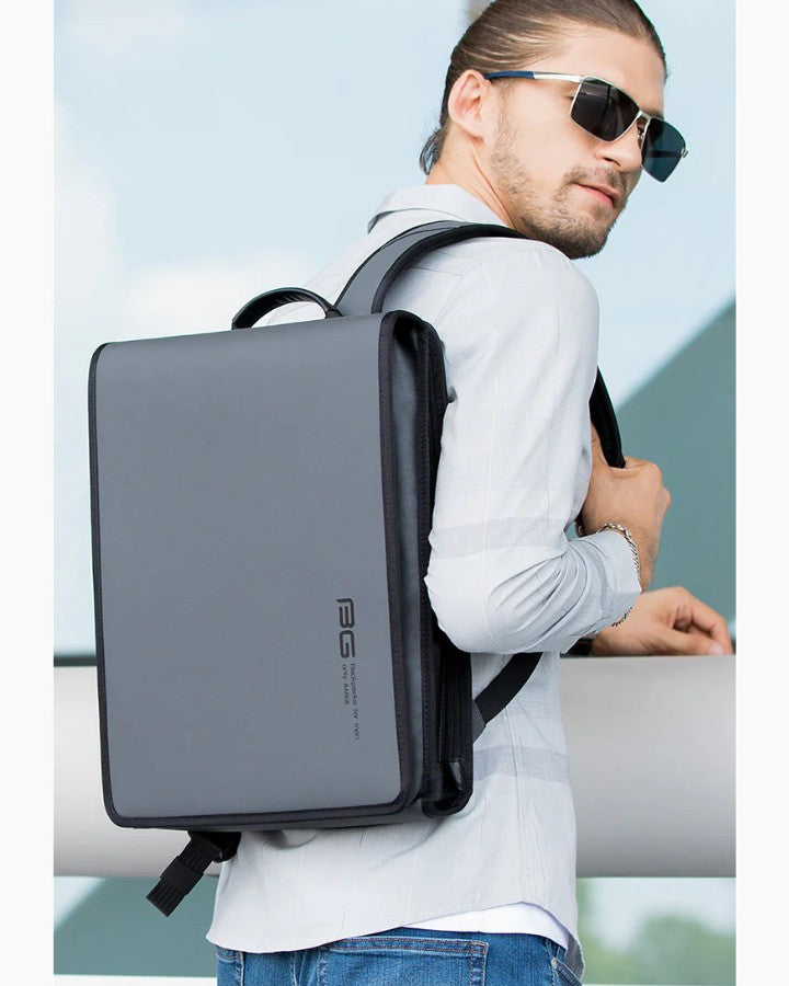 Homme portant un sac à dos plat pour ordinateur au design minimaliste et moderne.
