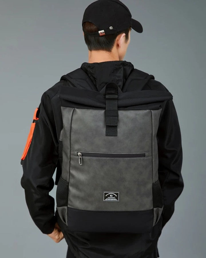 Sac à Dos Roll Top en Cuir, coloris gris foncé porté sur le dos d'un homme