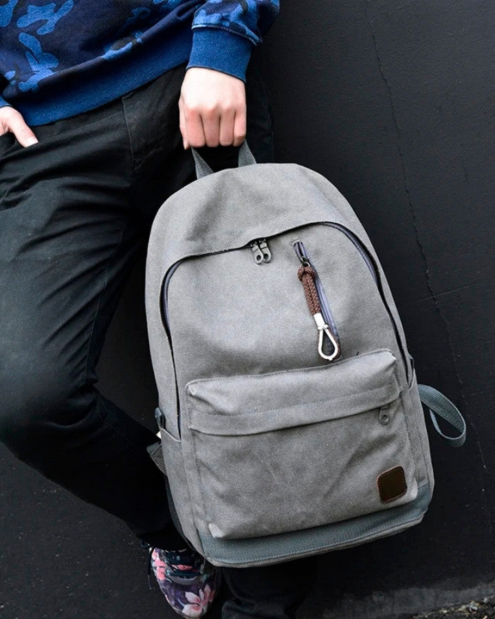 Sac à Dos Toile Canvas, gris, porté à la main d'un homme, tenu par la poignée de transport